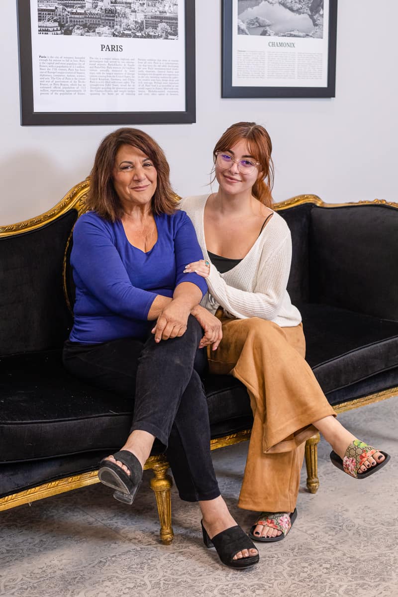 Mother and daughter sit on black sofa